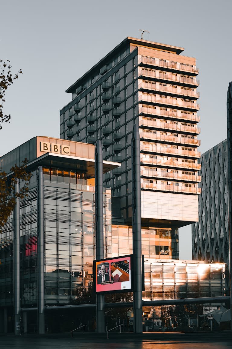 Captivating view of BBC's modern architecture at Salford Quays, Manchester, illuminated by warm sunset tones.